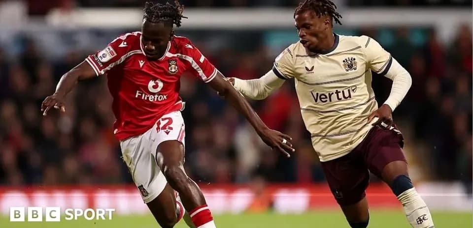 Jugador con camiseta roja driblando balón en el partido