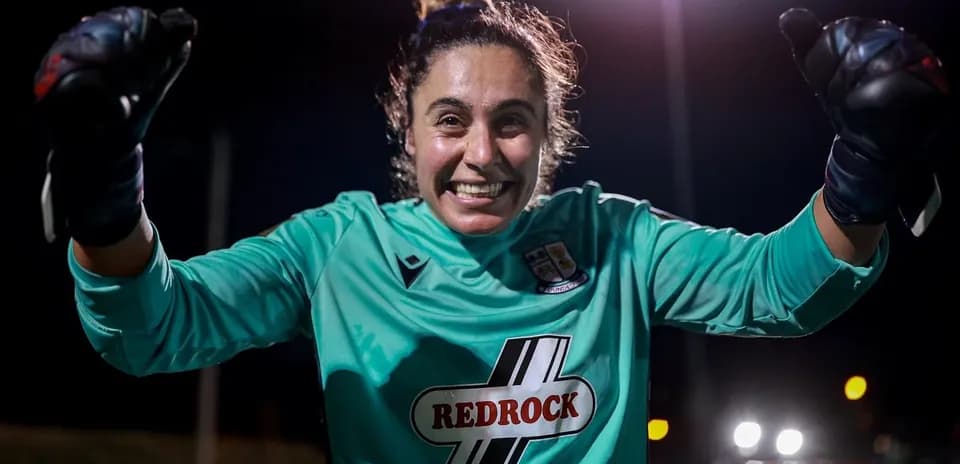 Portera celebrando con guantes en campo oscuro
