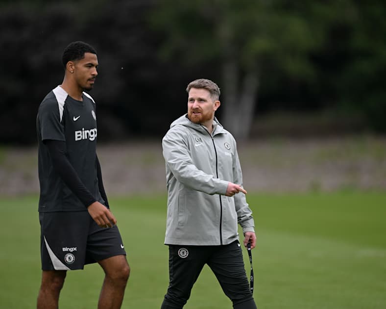 Jugador y entrenador conversando en campo de entrenamiento