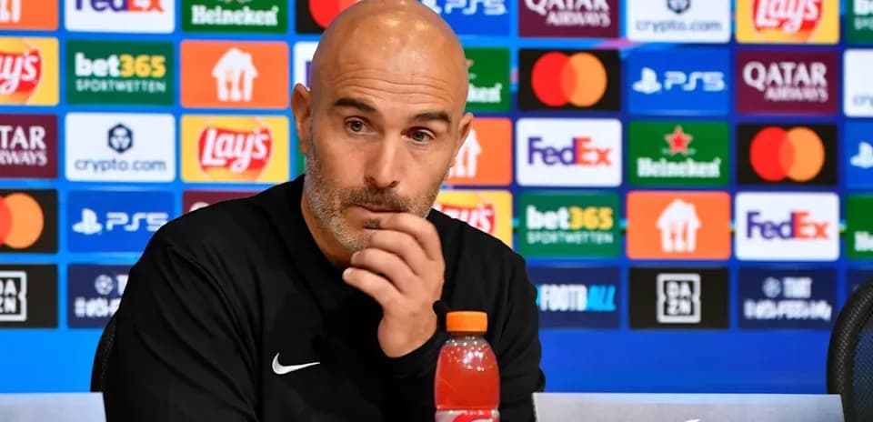 Entrenador en conferencia de prensa con patrocinadores de fondo
