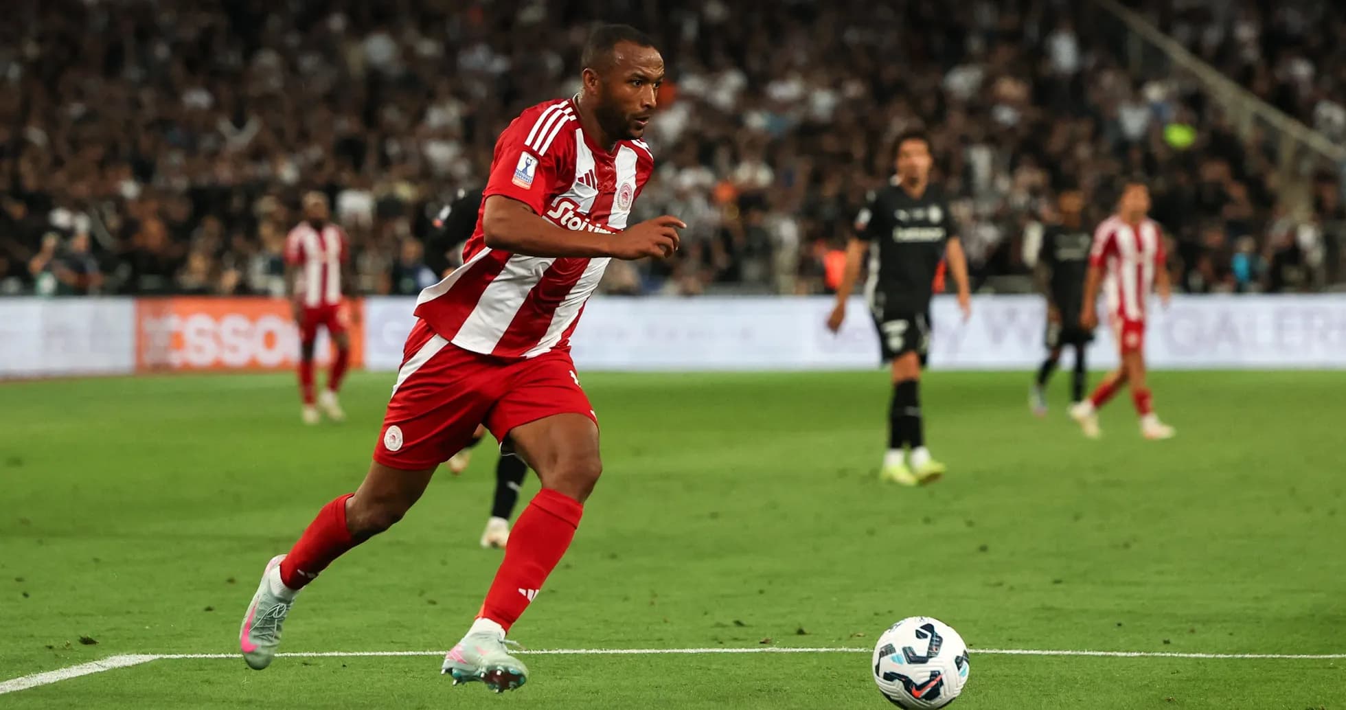 Jugador de Olympiacos corriendo tras el balón en campo