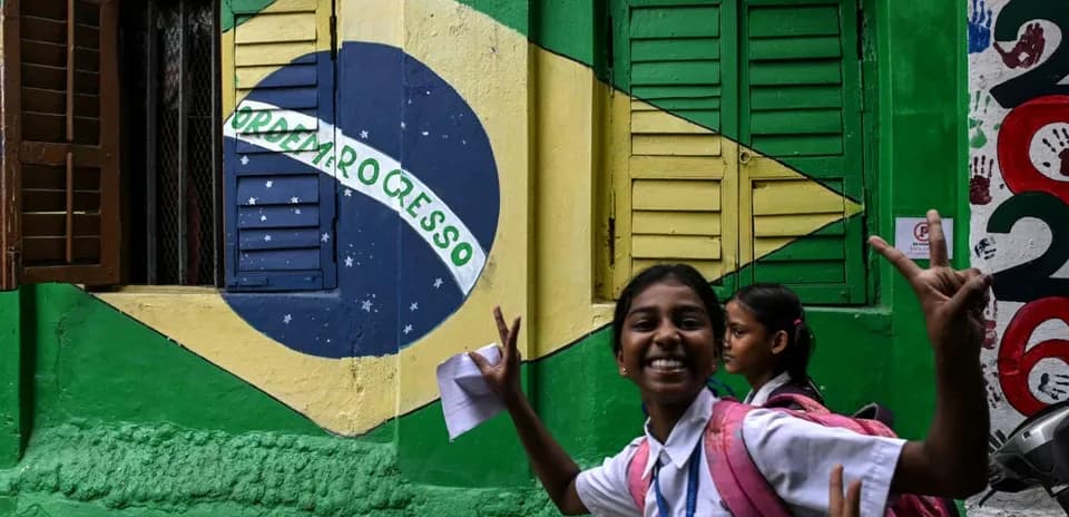 Niña sonriente frente a mural de bandera brasileña