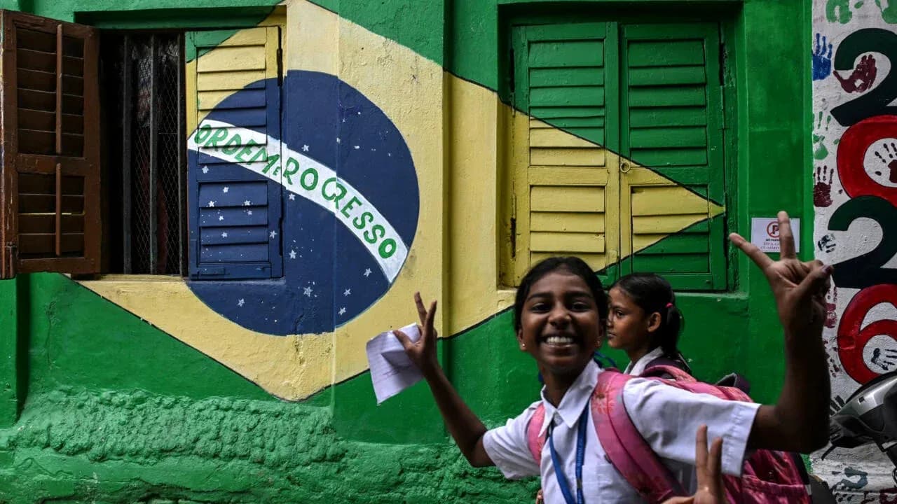 Niña sonriente frente a mural de bandera brasileña