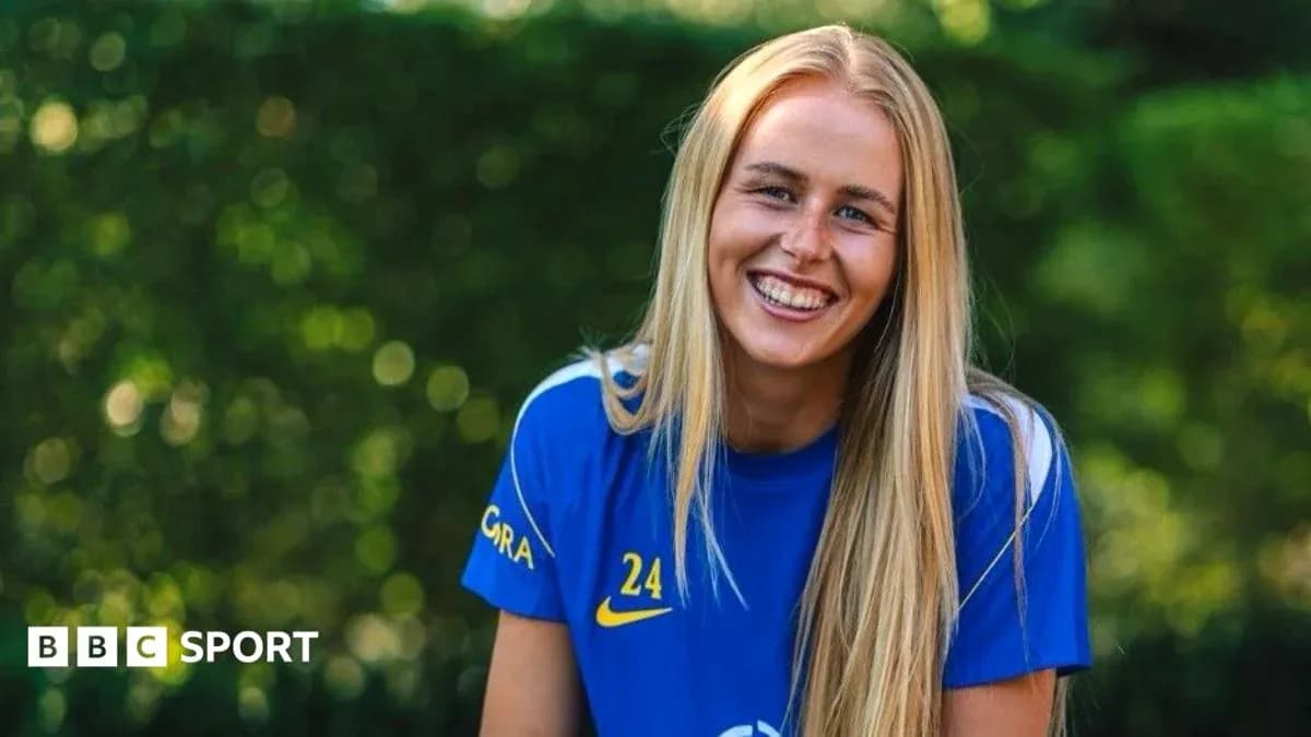 Jugadora de fútbol sonriendo en camiseta azul