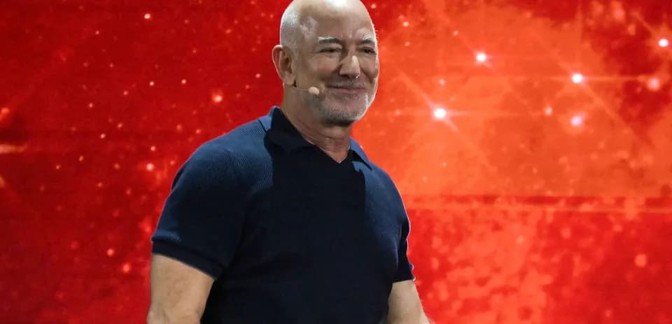 Hombre sonriendo en un escenario con fondo rojo