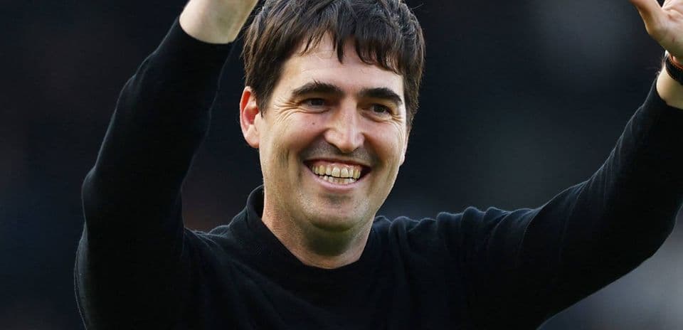 Entrenador sonriendo y saludando a los aficionados