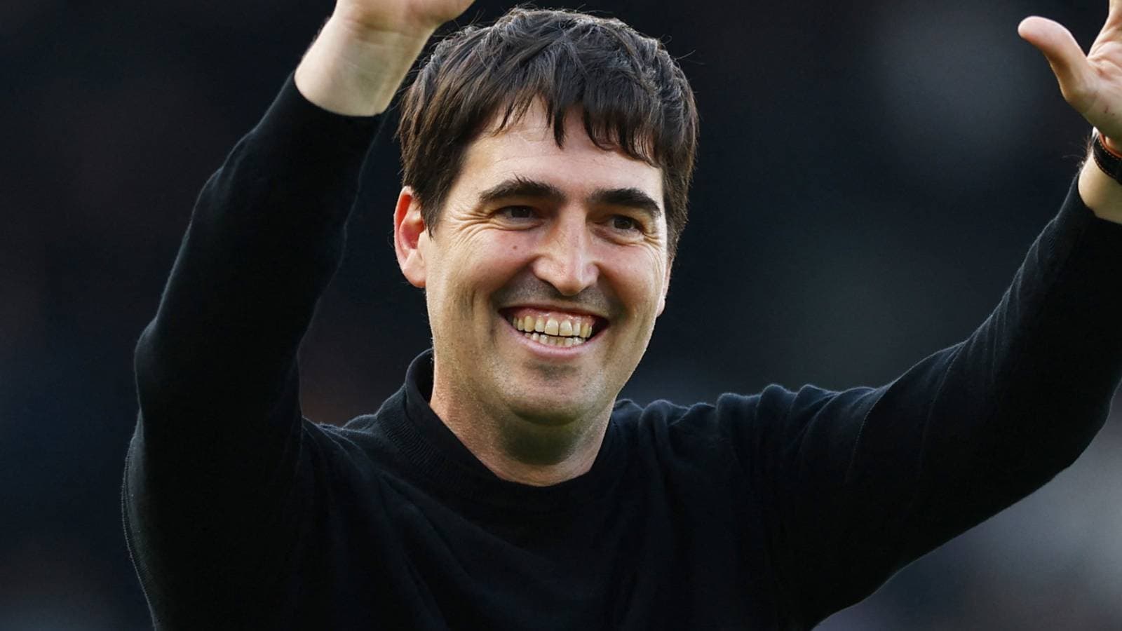Entrenador sonriendo y saludando a los aficionados
