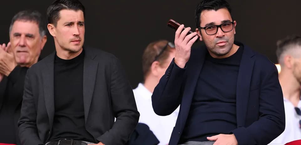 Dos hombres en la tribuna durante un evento deportivo