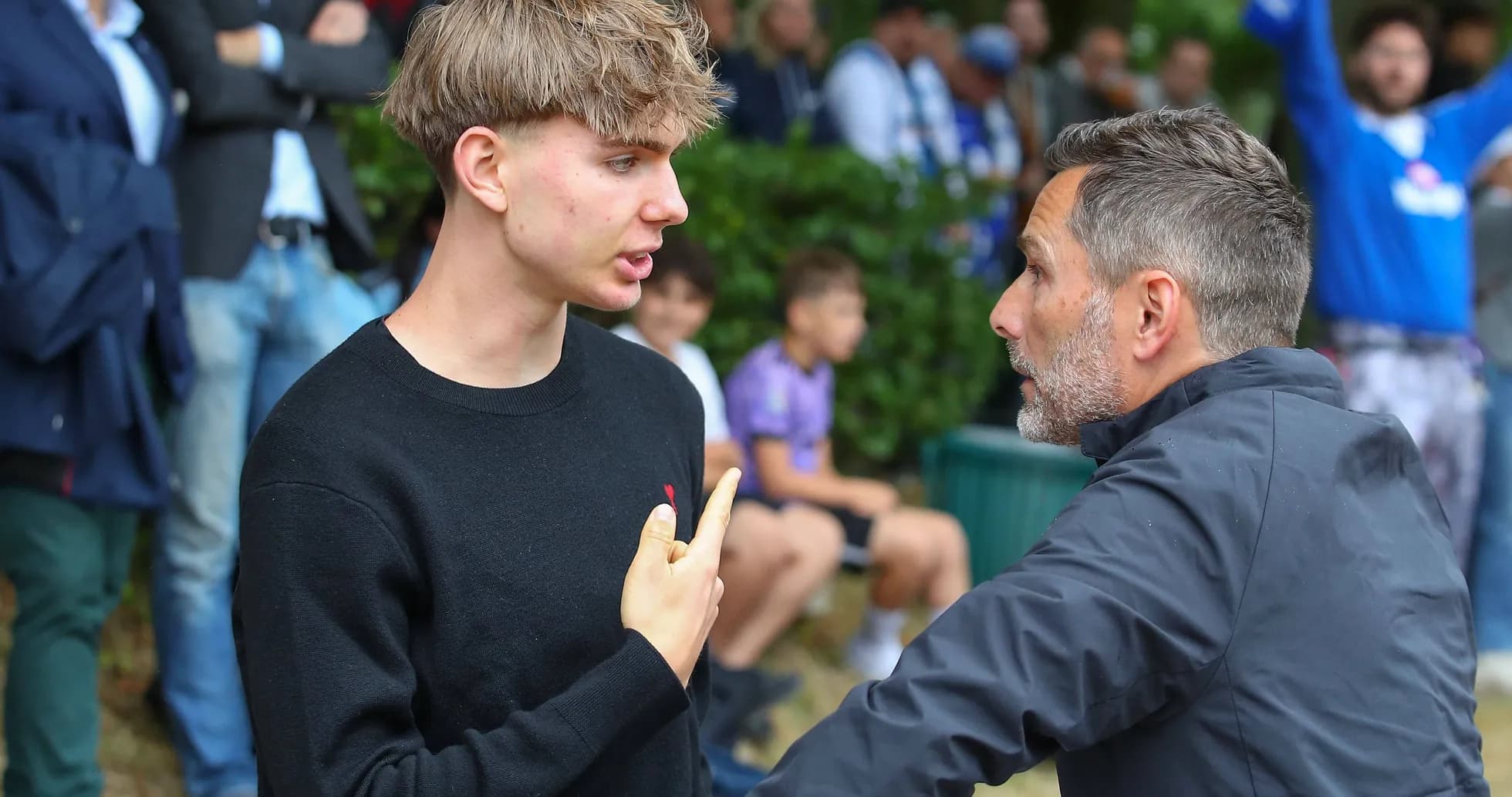 Dos hombres conversando en un evento deportivo