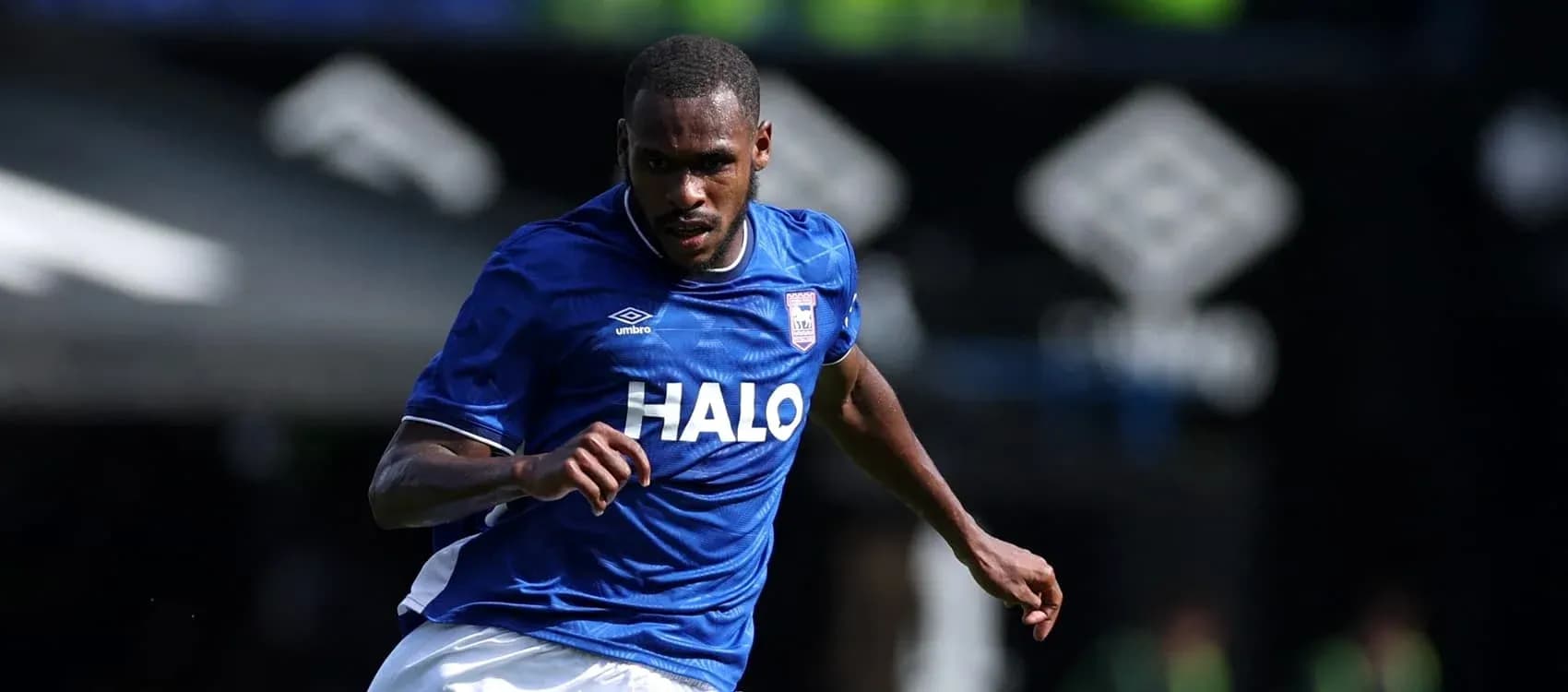 Jugador corriendo con balón en uniforme azul