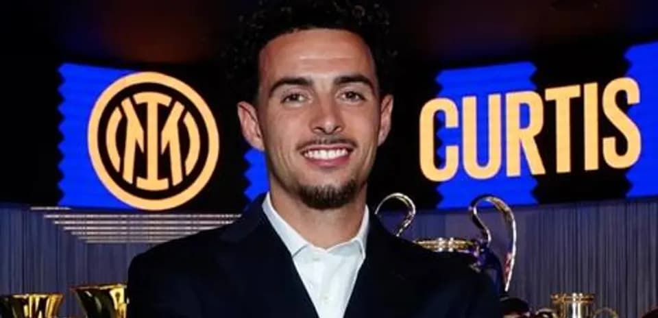 Jugador posando frente a trofeos y logo de Inter