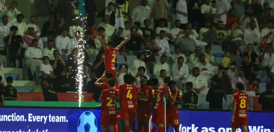 Jugadores celebrando un gol con fuegos artificiales