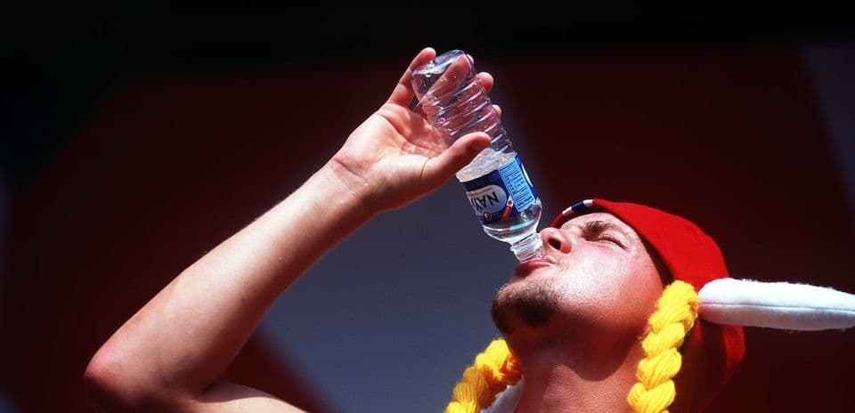 Hombre bebiendo agua de botella con gorra roja