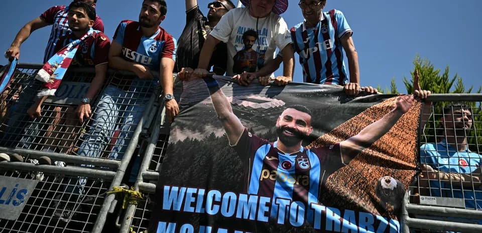 Aficionados sosteniendo un cartel de bienvenida a jugador