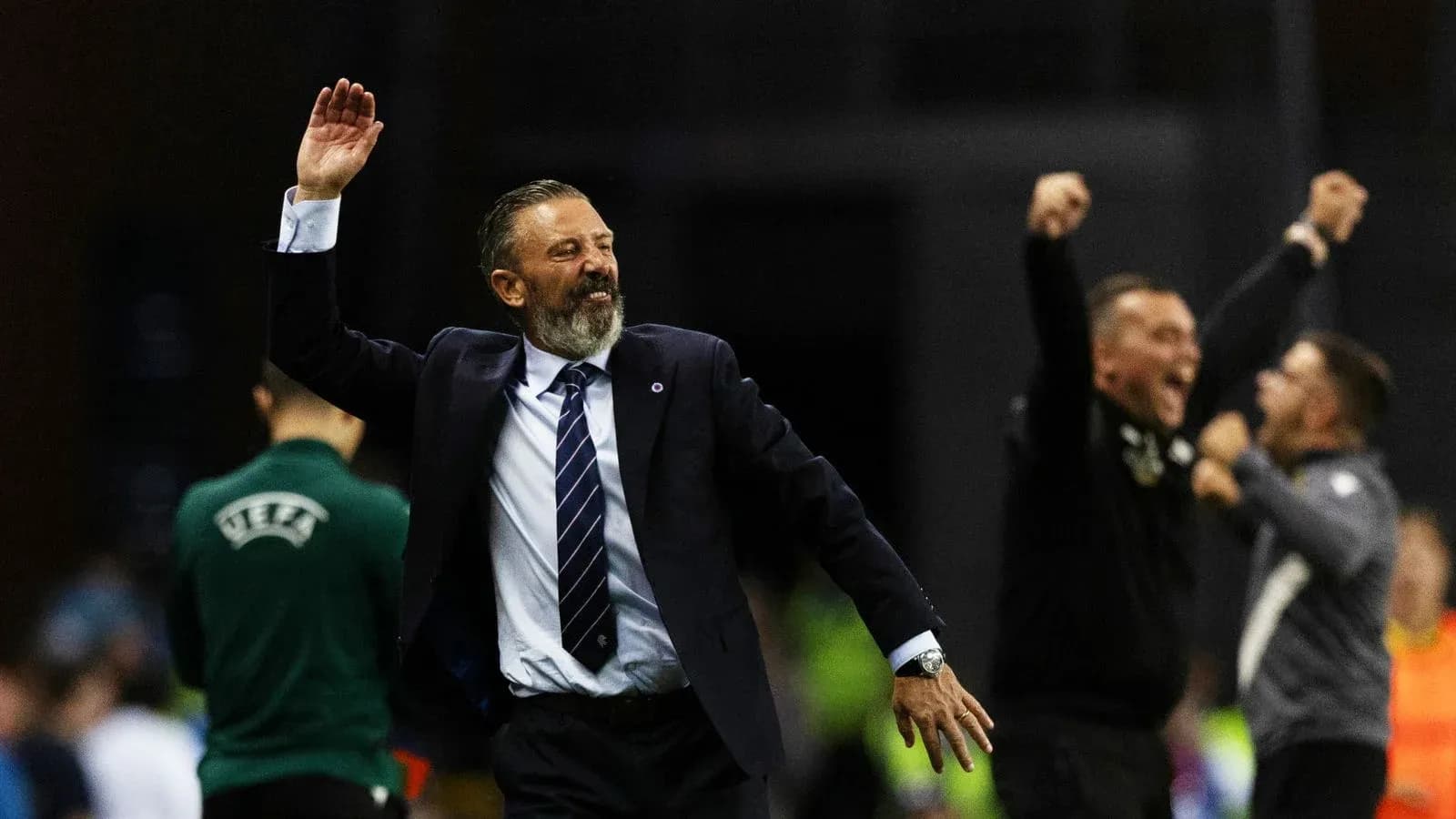 Entrenador celebrando con brazos alzados en la cancha