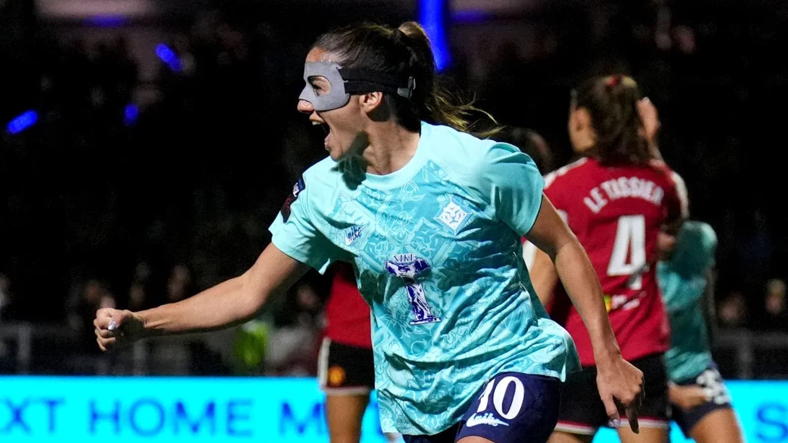 Jugadora celebrando un gol con máscara en partido