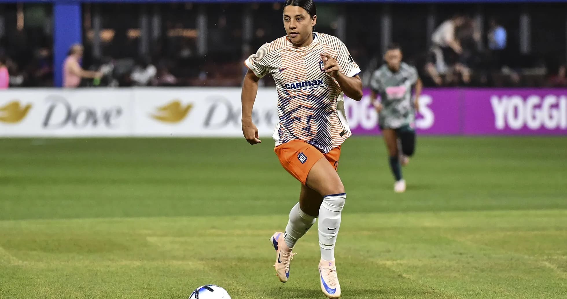 Jugadora corriendo con el balón en el campo