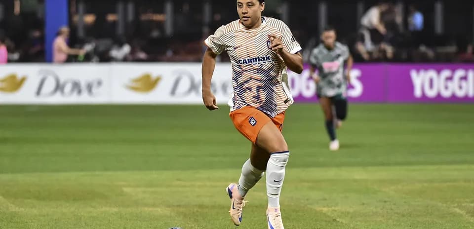 Jugadora corriendo con el balón en el campo