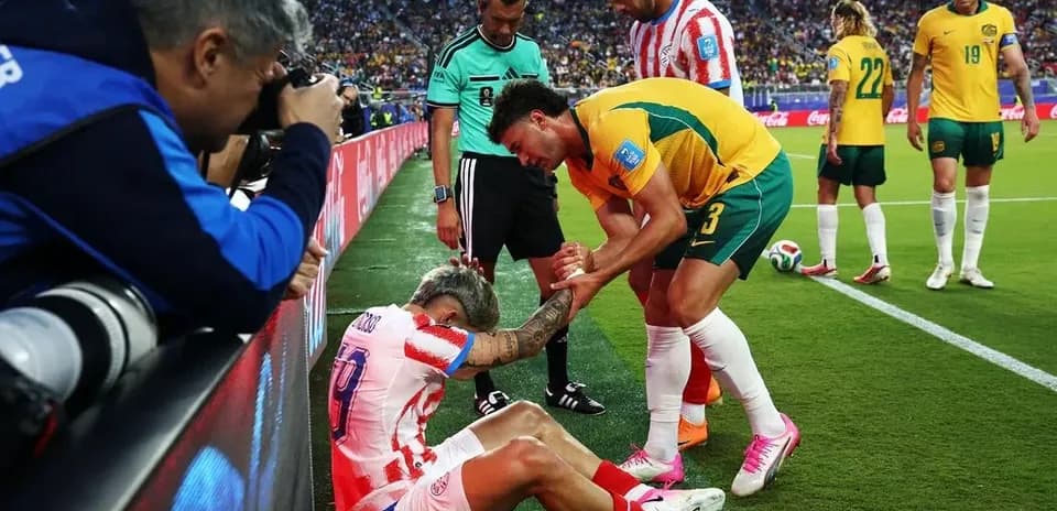 Jugador lesionado siendo asistido por rival y árbitro