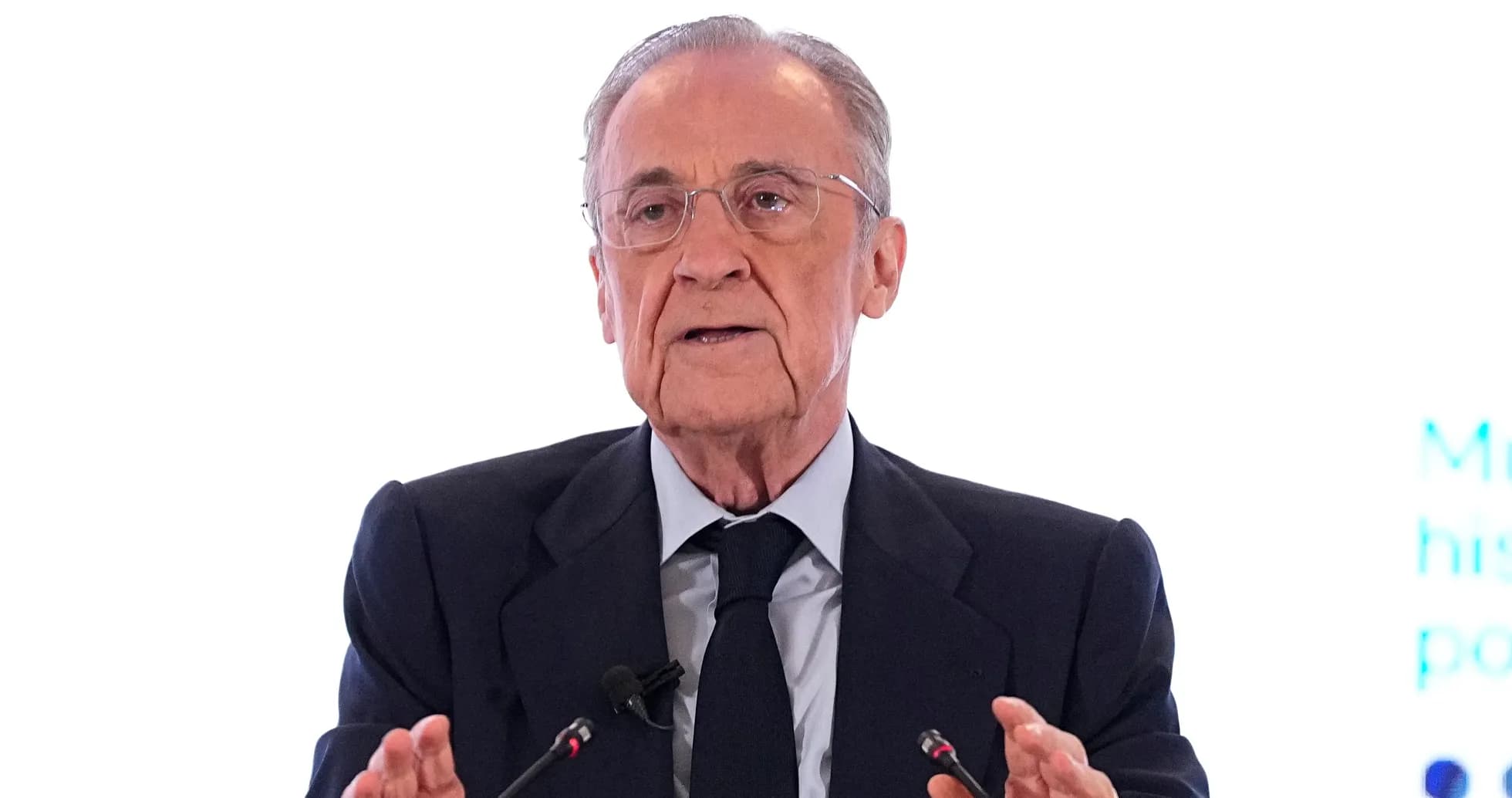 Hombre hablando en conferencia con micrófonos frente a él