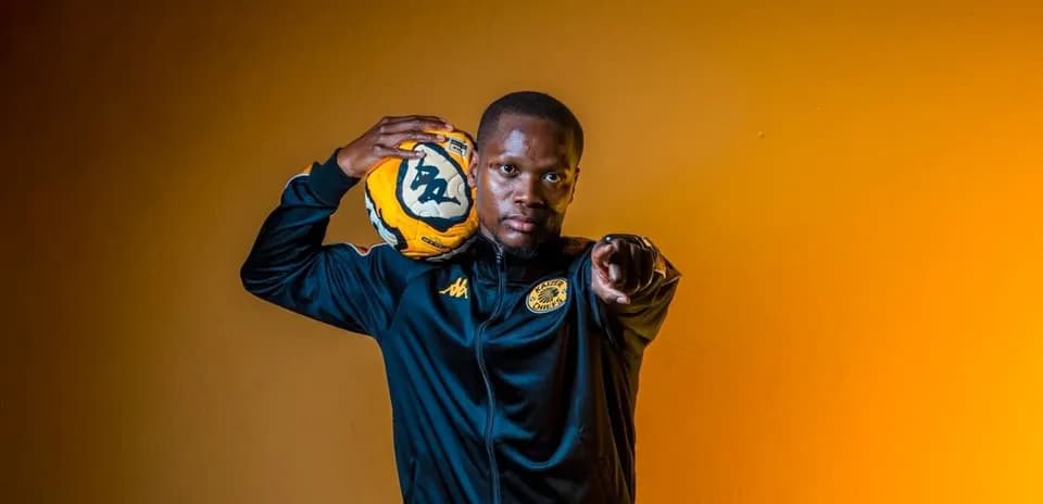 Jugador de fútbol con balón posando frente a fondo naranja