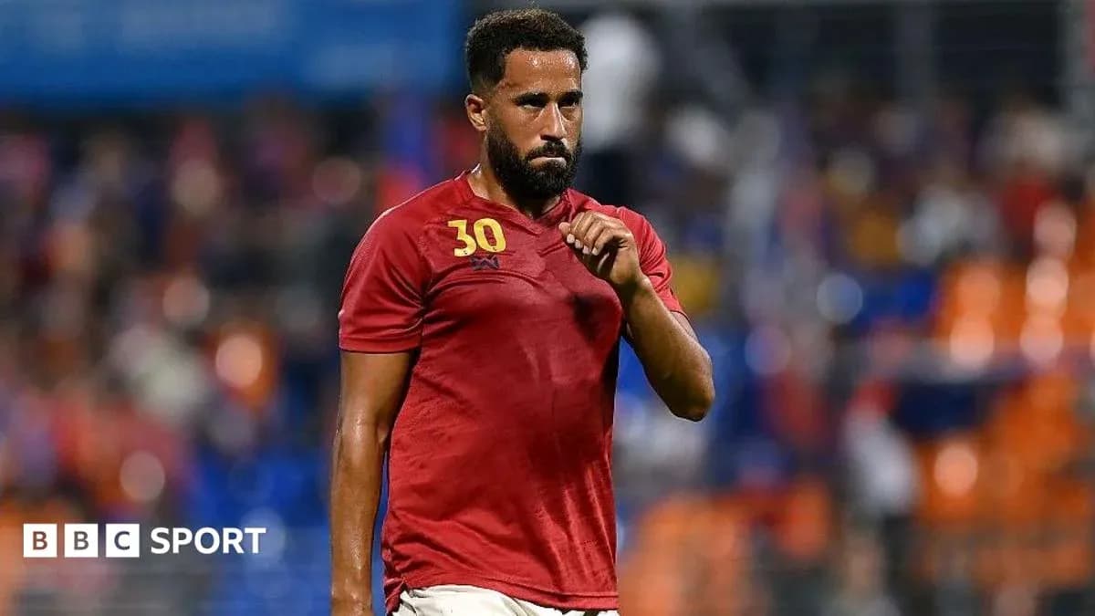 Jugador con camiseta roja caminando por el campo