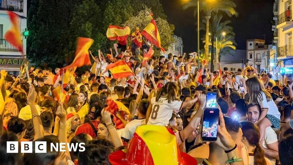 Multitud celebrando con banderas españolas en la calle