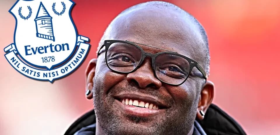 Hombre sonriendo con gafas y escudo de Everton
