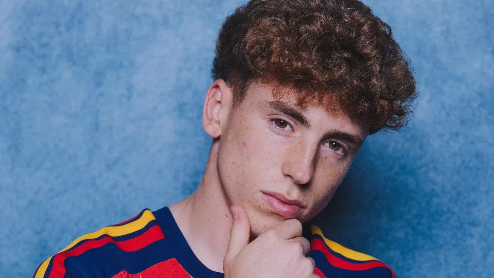 Joven con camiseta de rayas frente a fondo azul