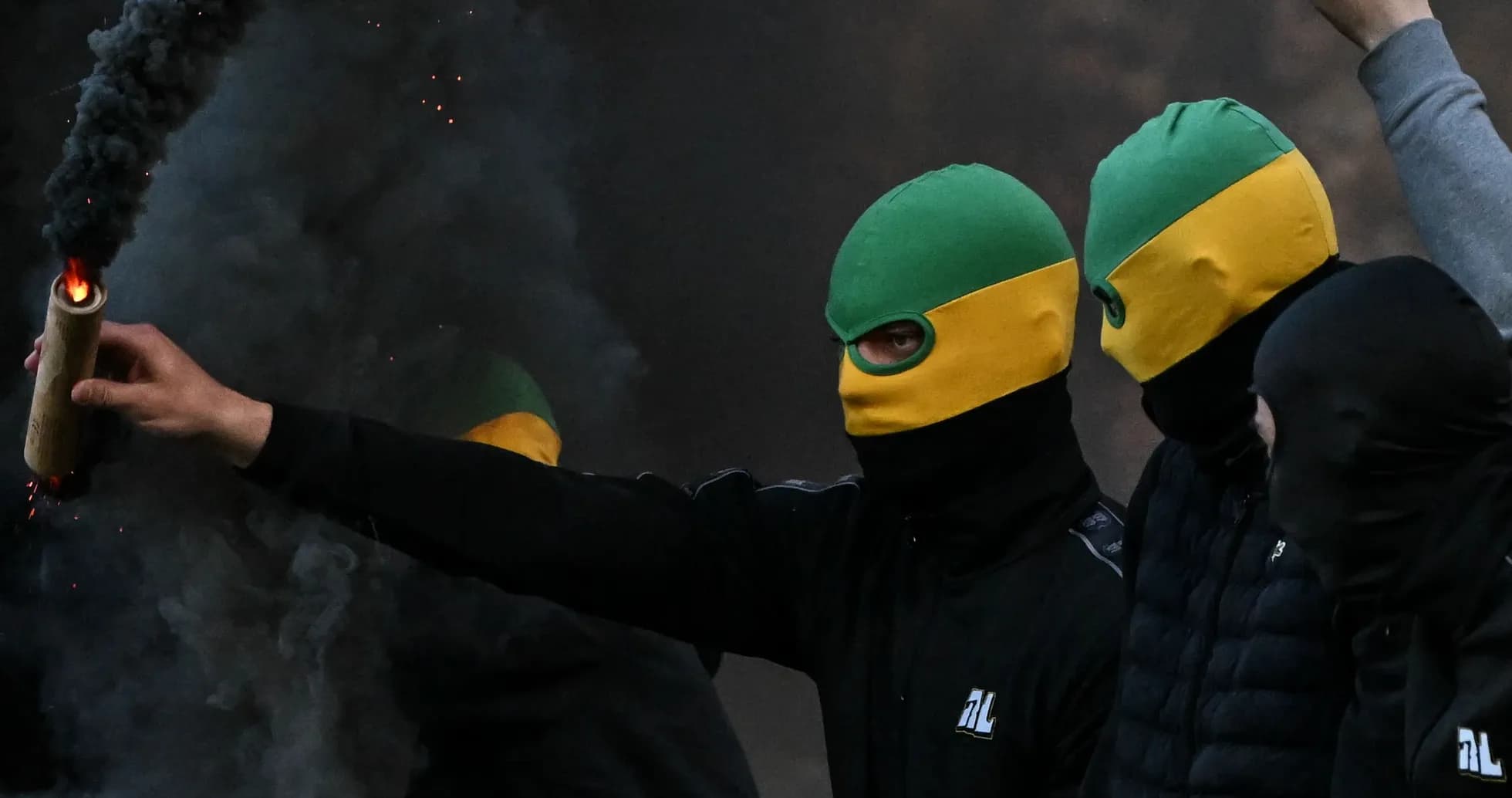 Grupo de personas con máscaras sosteniendo un objeto incendiario