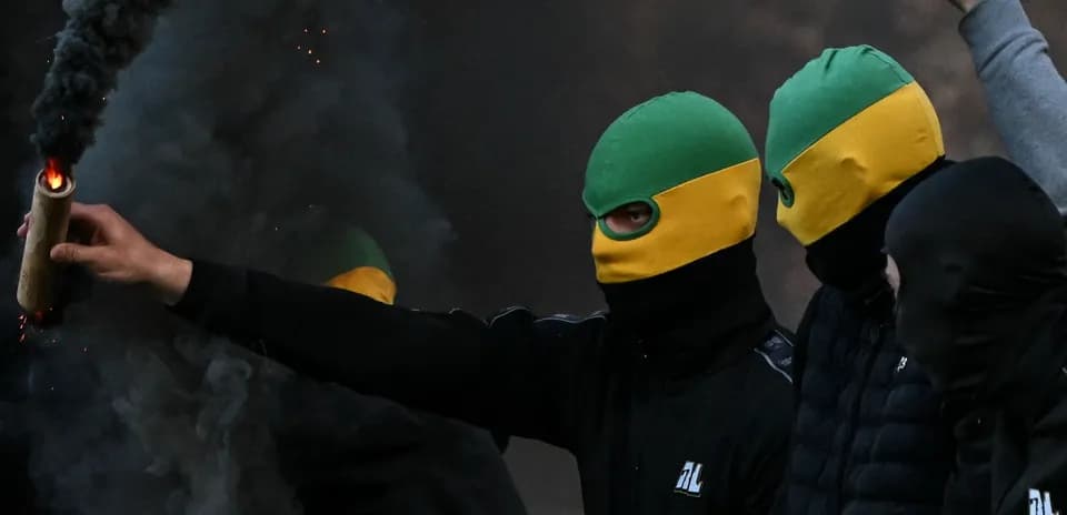 Grupo de personas con máscaras sosteniendo un objeto incendiario