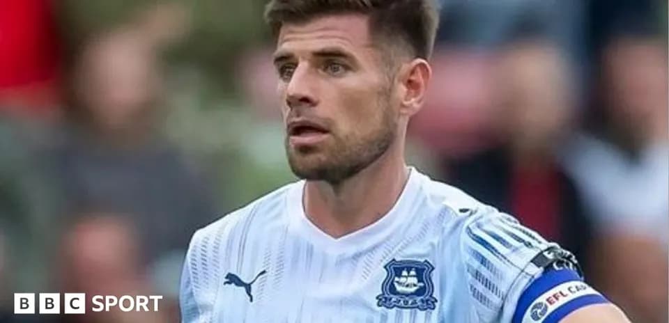 Jugador con camiseta blanca y brazalete de capitán
