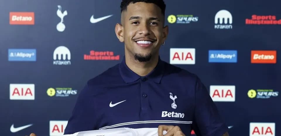 Jugador sonriente sosteniendo camiseta de Tottenham Hotspur