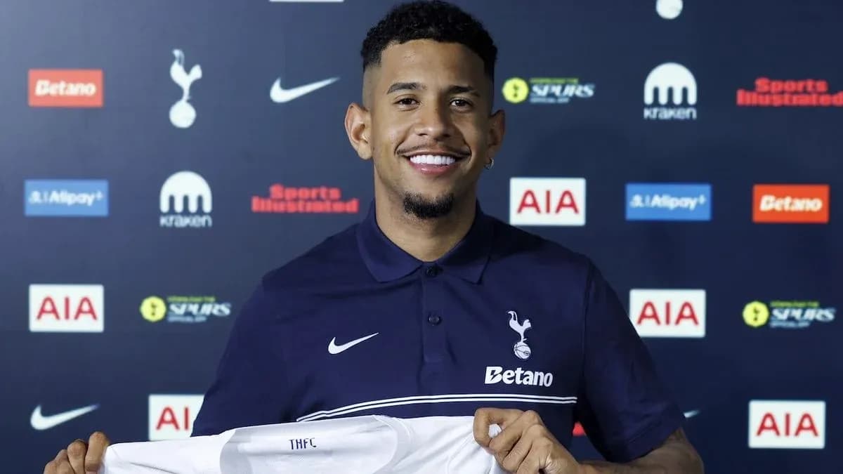 Jugador sonriente sosteniendo camiseta de Tottenham Hotspur