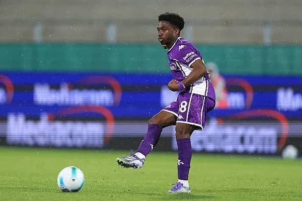 Jugador con balón en campo de fútbol lluvioso