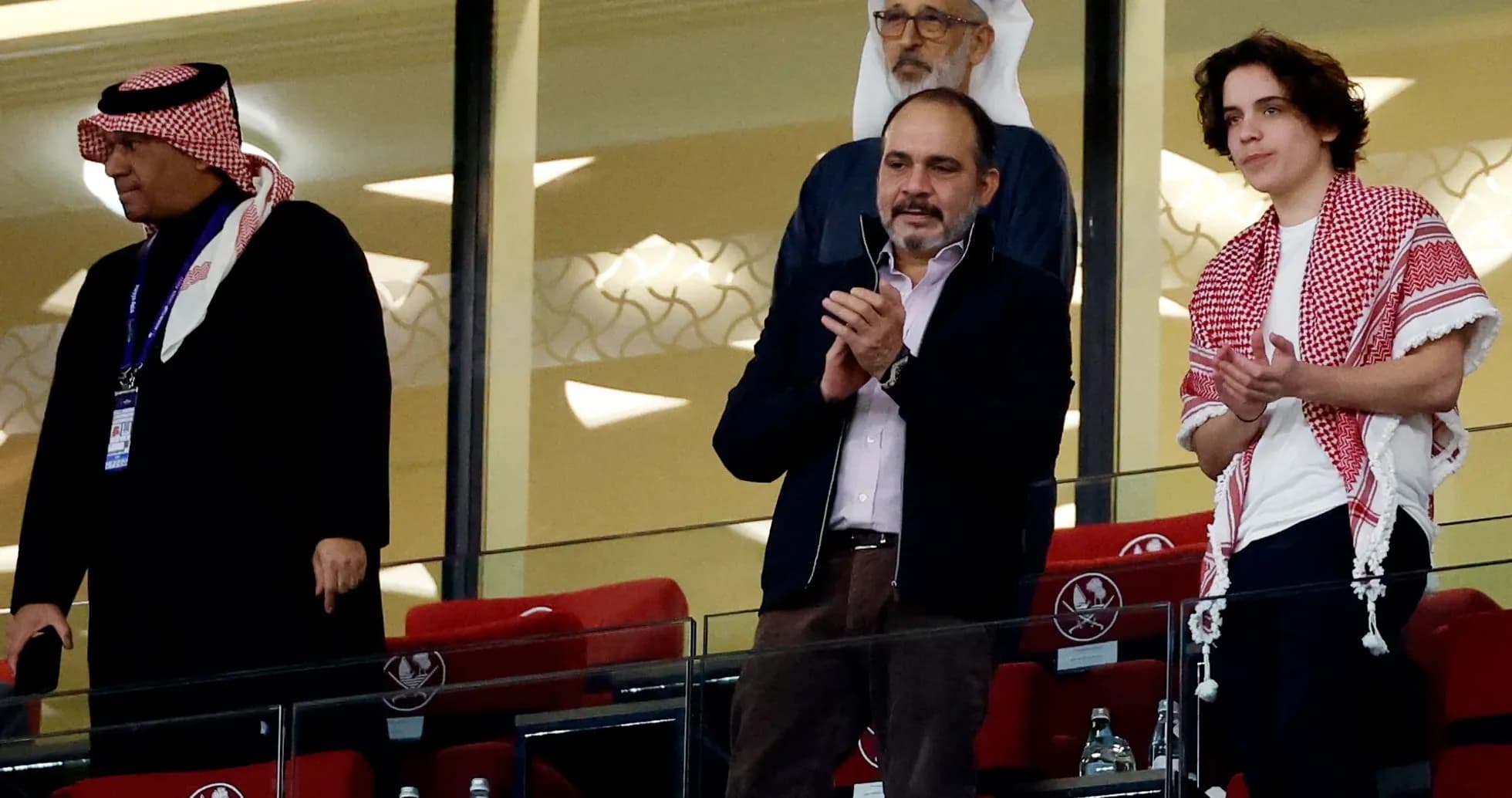 Cuatro hombres aplaudiendo en un palco de estadio