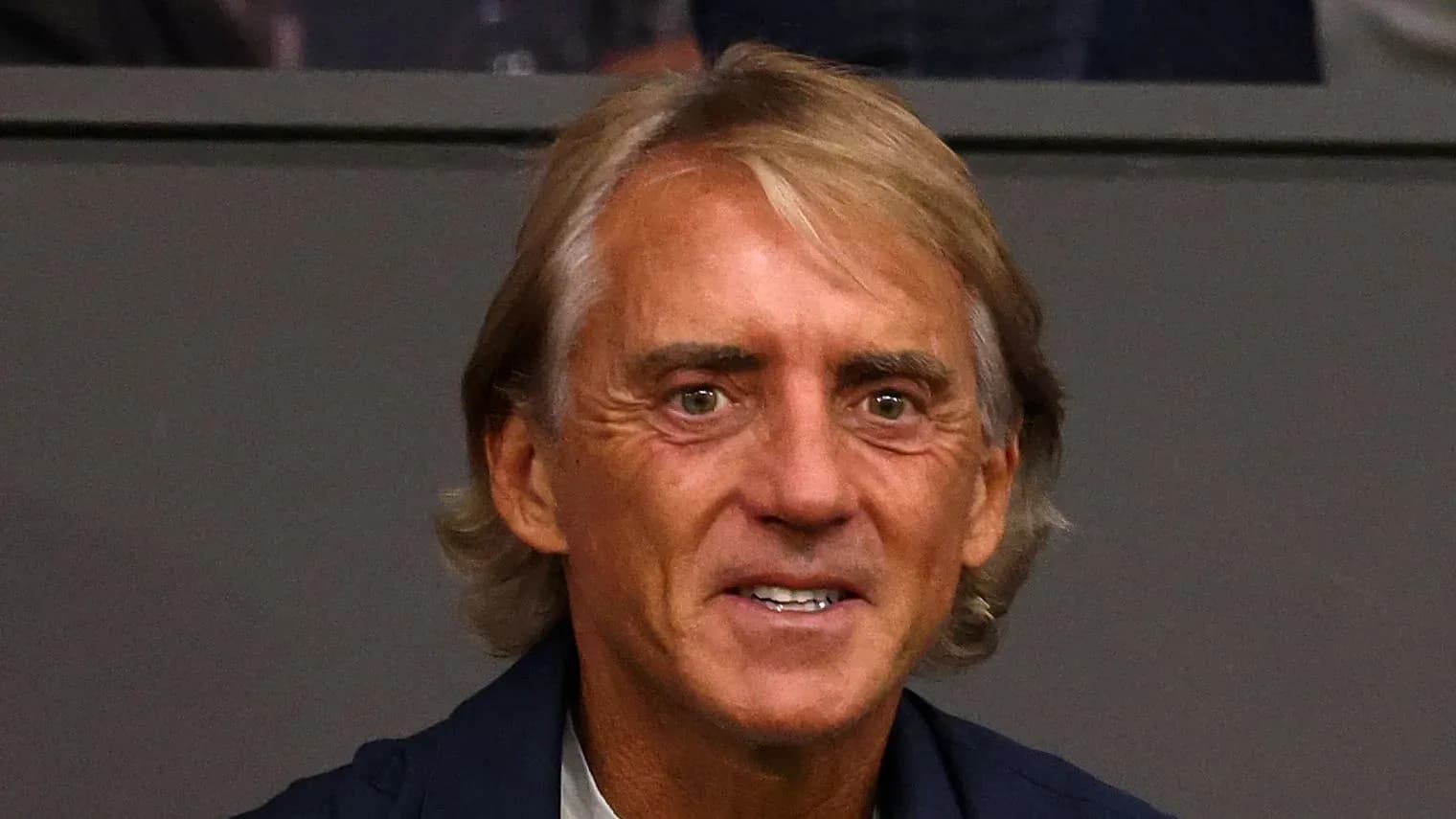 Hombre con cabello rubio sentado en un estadio