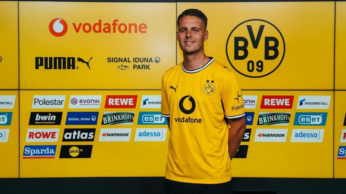 Jugador posando en conferencia de prensa con camiseta de Borussia Dortmund