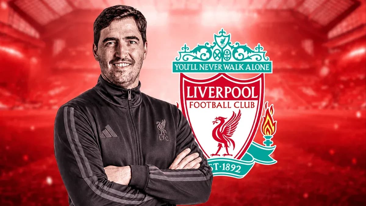 Entrenador posando frente al escudo de Liverpool FC