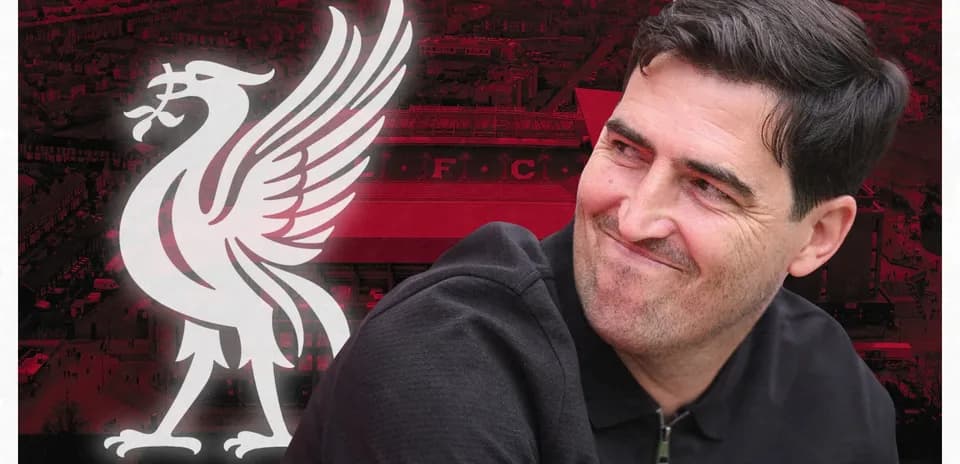 Entrenador sonriendo frente al logo del Liverpool