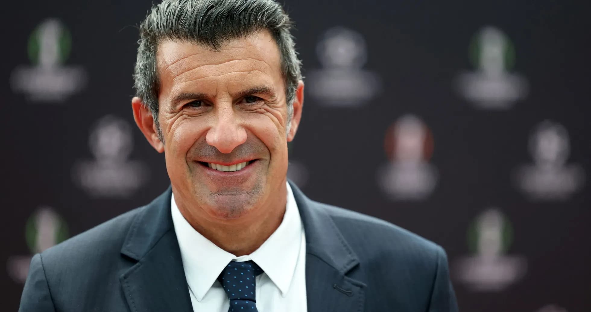 Hombre sonriendo en evento deportivo con fondo oscuro