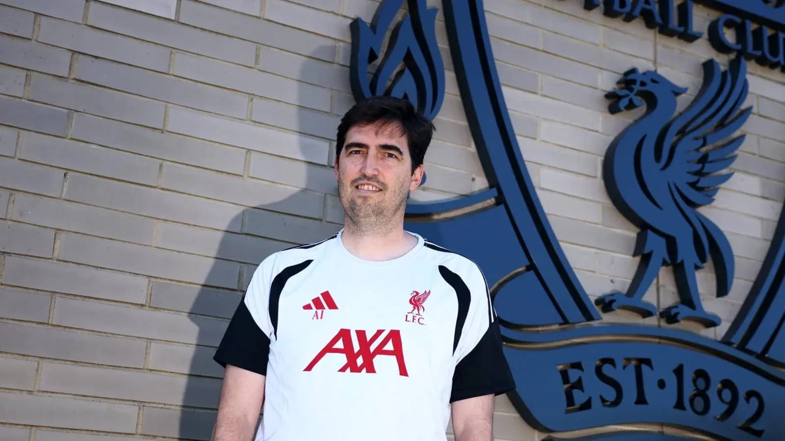 Persona posando frente al escudo del Liverpool FC