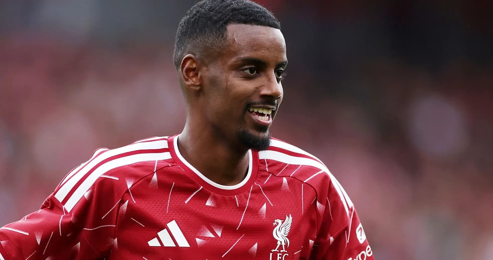 Jugador de Liverpool sonriendo en uniforme rojo