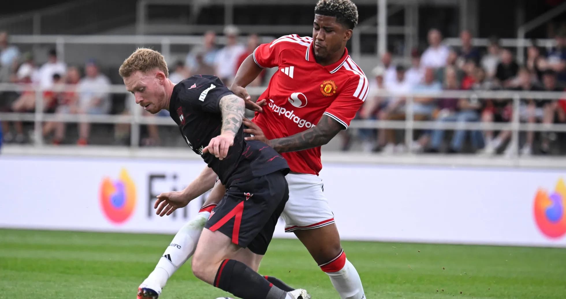 Jugador de Manchester United presionando a oponente en el suelo
