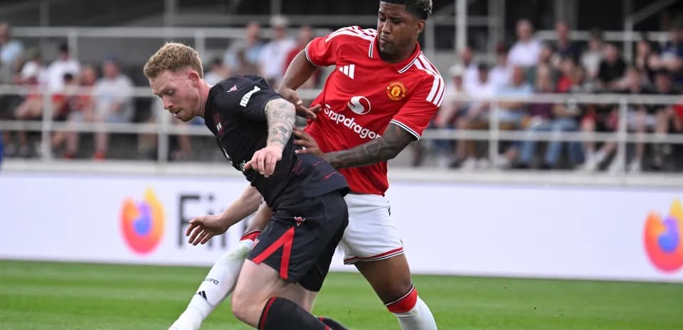 Jugador de Manchester United presionando a oponente en el suelo