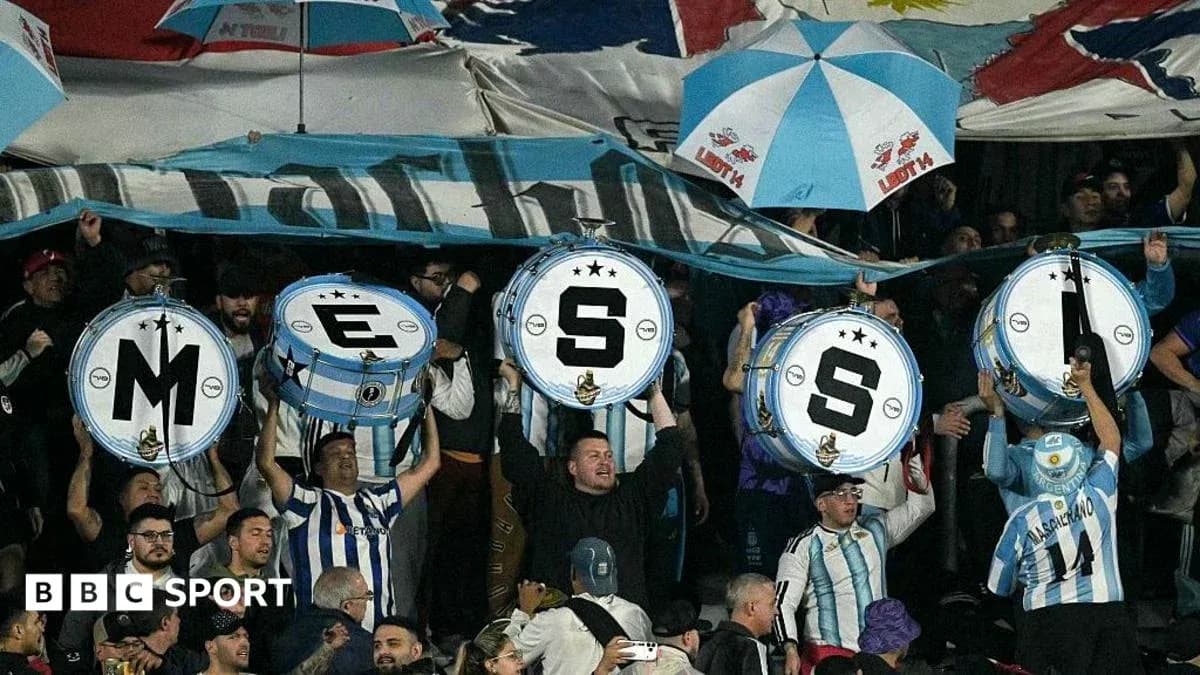 Aficionados sosteniendo tambores con letras en un partido