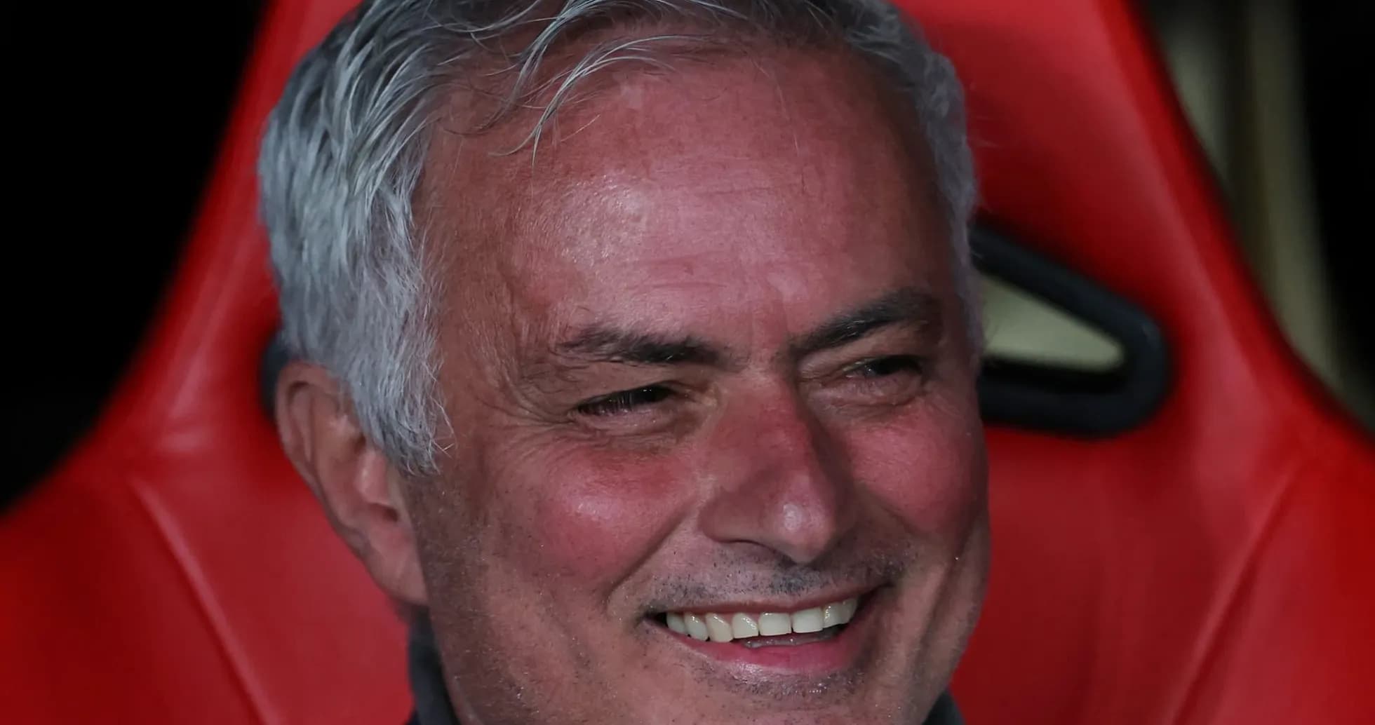 Entrenador sonriendo en el banquillo del partido