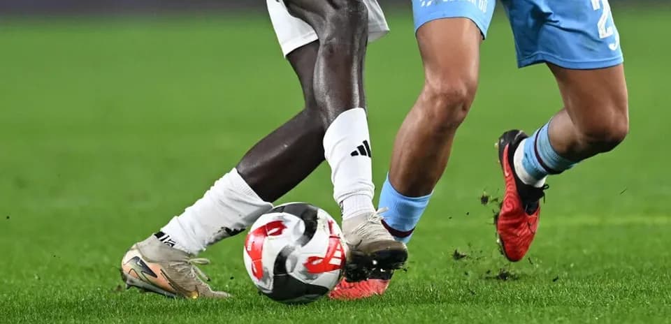 Dos jugadores compitiendo por el balón en el campo