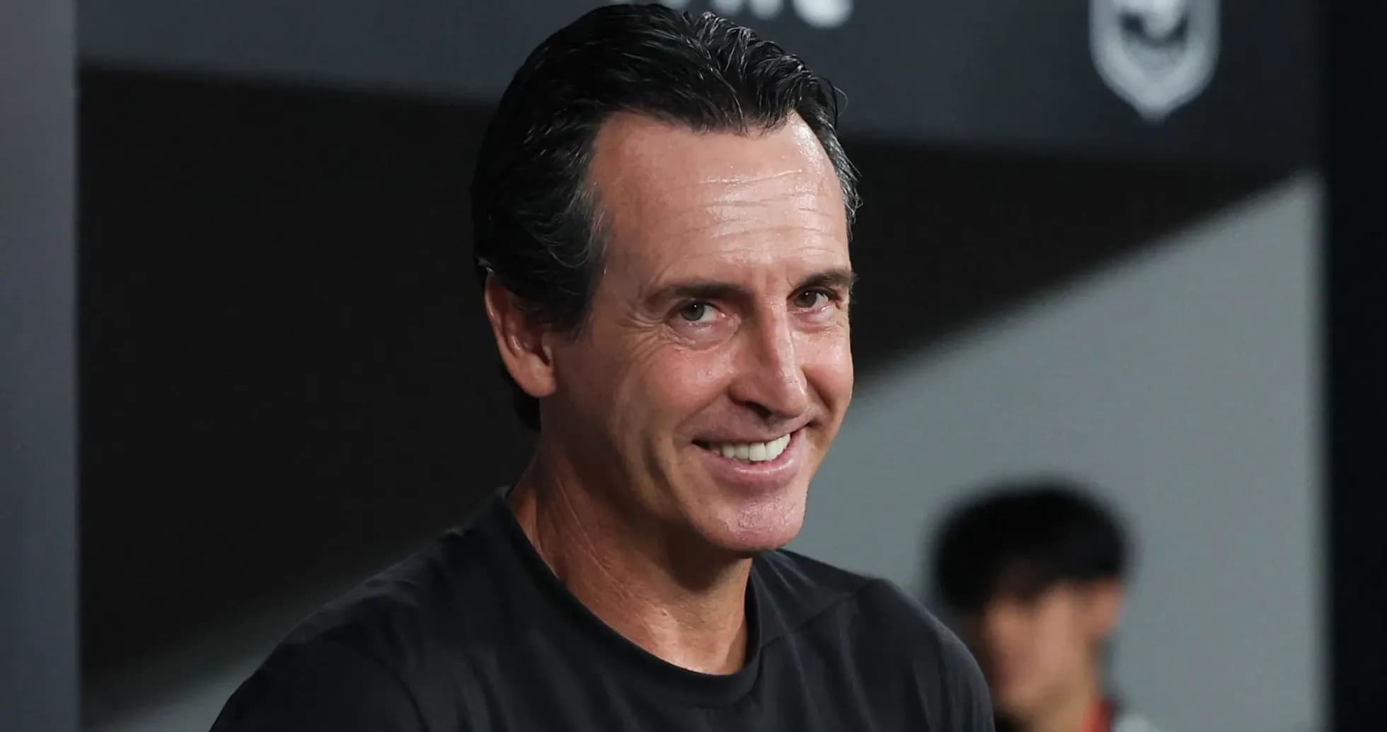 Entrenador sonriendo en el banquillo del estadio