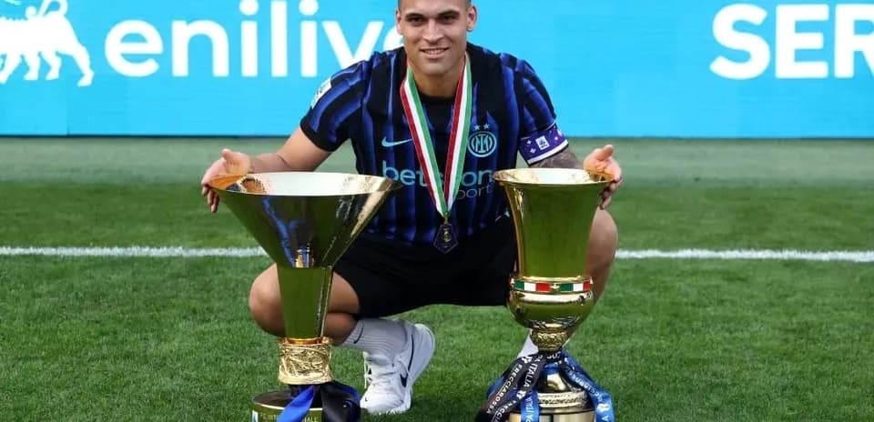 Jugador con dos trofeos en campo de fútbol